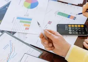 A close-up of businesspeople analyzing financial data and charts during a meeting.